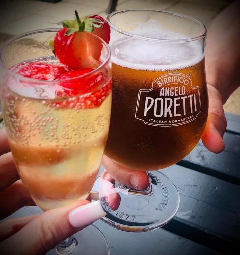 a person holding a glass of beer with a strawberry in it at The Kings Arms - Fleggburgh in Burgh Saint Margaret