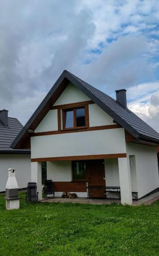 a white house with a dog laying in the yard at Domki - Noclegi Pod Ostrym Działem in Ustrzyki Dolne