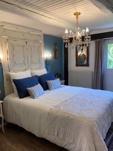 ein Schlafzimmer mit einem großen Bett mit blauen Wänden und einem Kronleuchter in der Unterkunft La Ferme de Grand Mère in Furchhausen