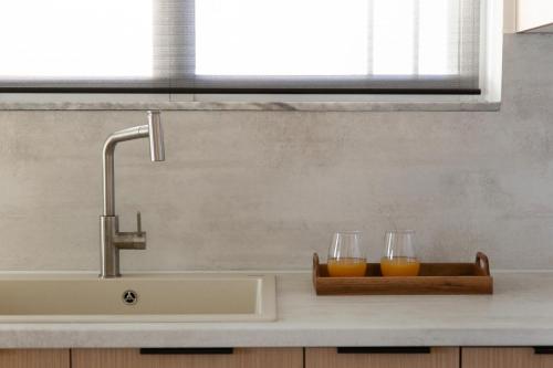 two glasses of orange juice on a counter next to a sink at Seafront Luxury Suite in Rethymno Town