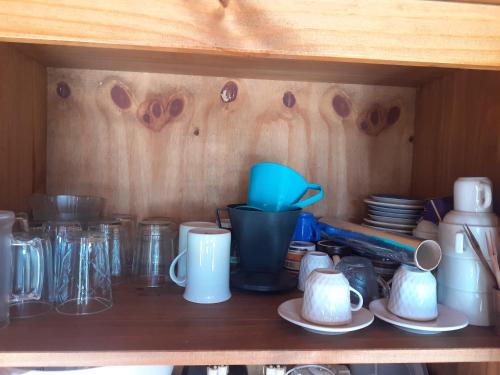 a wooden shelf with cups and mugs on it at Pousada Acolhedora in Ribeirão Preto