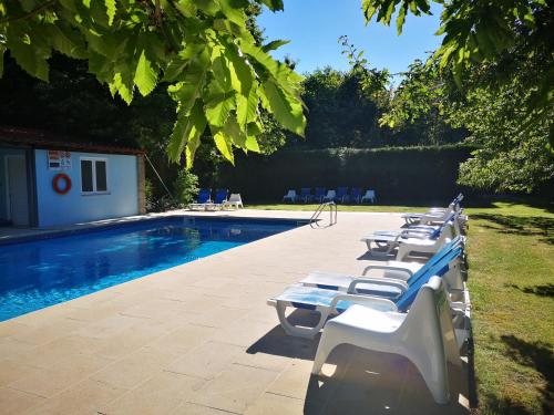 - une rangée de chaises longues blanches à côté de la piscine dans l'établissement T0 Eira Trás, à Vieira do Minho