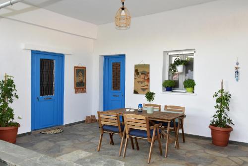 Kampos Family Garden في باتسي: غرفة طعام ذات أبواب زرقاء وطاولة وكراسي