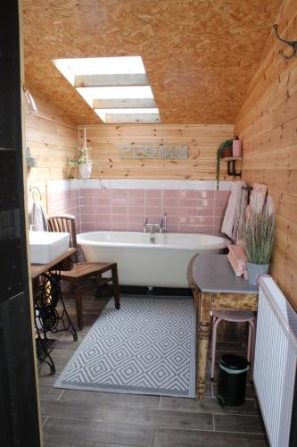ein Badezimmer mit einer Badewanne, einem Tisch und einem Waschbecken in der Unterkunft Green Rabbit Glamping in Diss