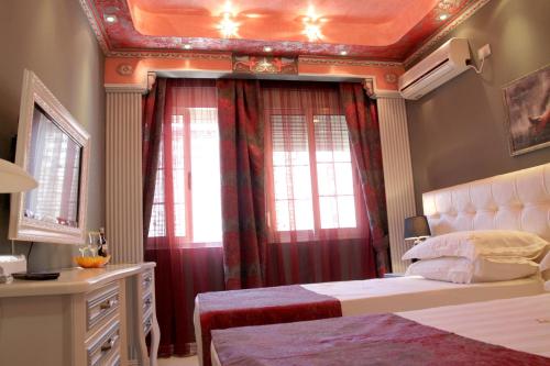 a bedroom with a bed with red curtains and a window at Hotel Boutique Vila Fernando Tirana in Tirana