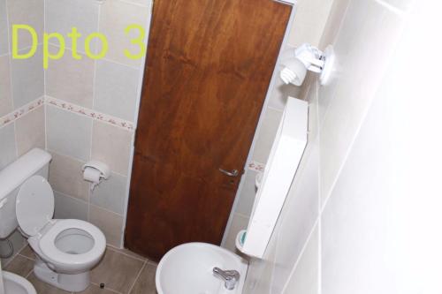 Un baño con inodoro y puerta de madera. en Apartamento El Calvario 3, en Tandil