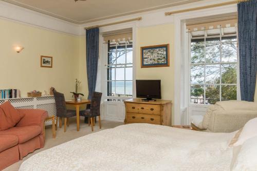 a bedroom with a bed and a desk and a tv at Lammas Park House in Dawlish