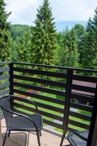 two chairs on a balcony with trees in the background at Willa Monti in Szczyrk