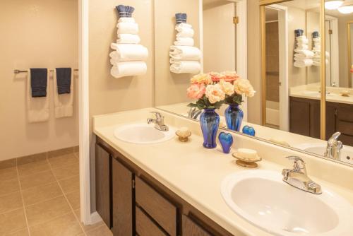 Baño con 2 lavabos y un jarrón de flores en Thunderbird Resort Club, en Reno