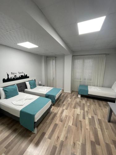 two beds in a room with wooden floors at Hotel New York in Kamëz