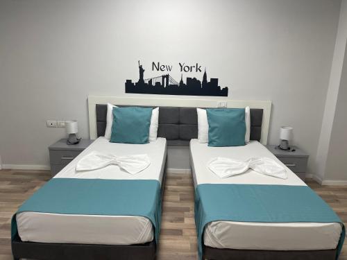 two beds in a room with a new york sign on the wall at Hotel New York in Kamëz