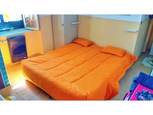 un letto in una camera con copriletto arancione di SPICCHIO DI MARE -vista mare- a Vietri