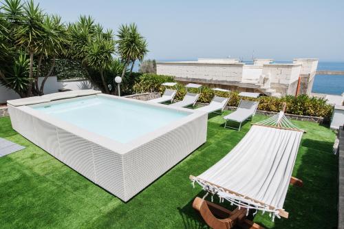 a pool on a lawn with chairs and a hammock at Villa Nicole Vista Mare in Andrano