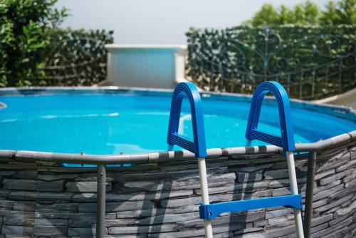 a swimming pool with two blue chairs next to it at Villa Nicole Vista Mare in Andrano