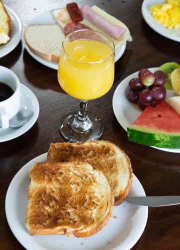 a table with plates of toast and a glass of orange juice at Tezla Hotel in Primavera do Leste