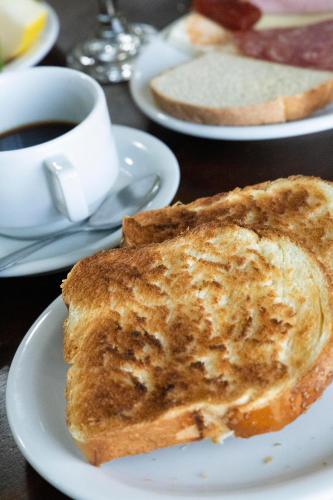 two pieces of toast on a plate with a cup of coffee at Tezla Hotel in Primavera do Leste