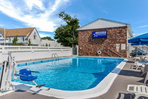 a swimming pool with blue water in front of a brick building at Americas Best Value Inn Hyannis in Hyannis