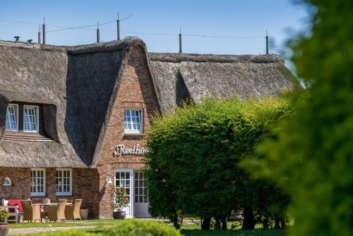 a house with a thatched roof with chairs in front at Hotel Reethüüs in Kampen