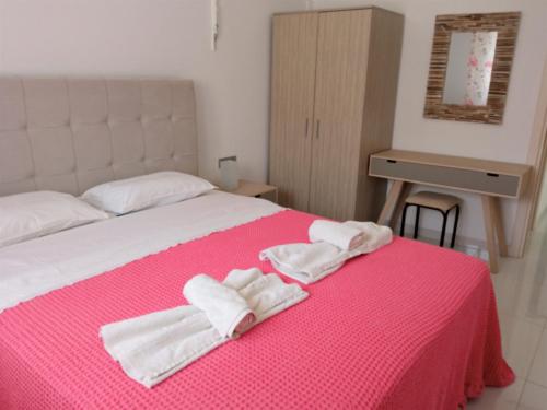 a bedroom with a pink bed with towels on it at Marion Holiday House in Alykes