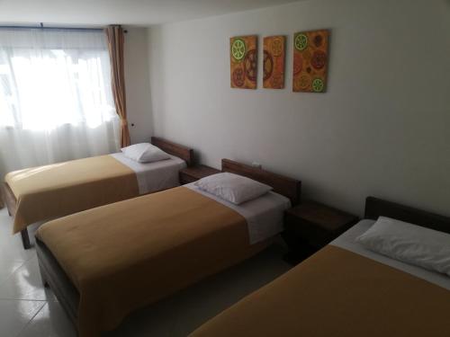 a hotel room with three beds and a window at HOTEL LA RUEDA SR in Barbosa