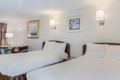 a hotel room with two beds and a table at Americas Best Value Inn Hyannis in Hyannis