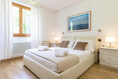 ein weißes Schlafzimmer mit einem großen weißen Bett mit zwei Lampen in der Unterkunft Apartment Gli Ulivi 4 - Tremezzina in Tremezzo