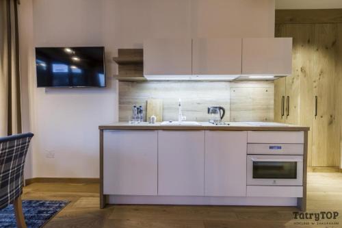 a kitchen with white cabinets and a sink at Tatra Resort & SPA in Kościelisko