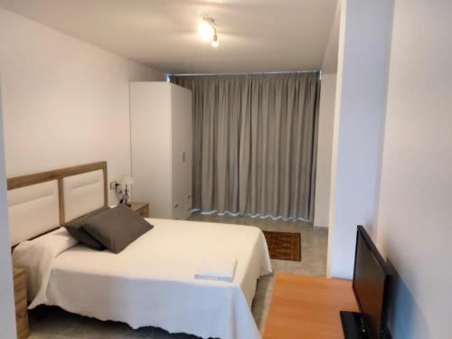 a bedroom with a white bed and a television at A Casa de Lolita in Muros