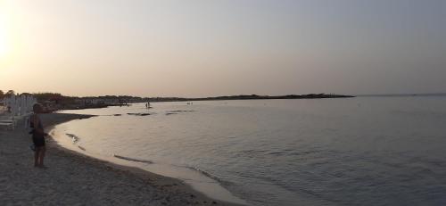 a man standing on a beach near the water at b&b Stella marina torre guaceto in Specchiolla 