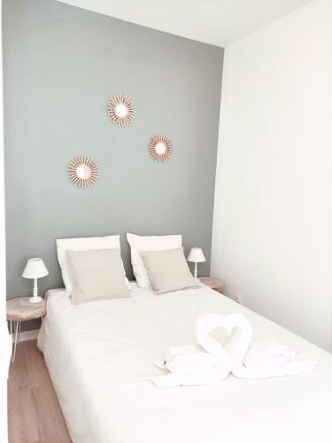 een slaapkamer met een wit bed en 2 spiegels aan de muur bij Aéroport Roissy CDG - Parc Astérix - Parc des expositions in Louvres