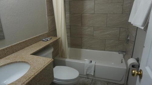 a bathroom with a toilet and a sink and a tub at La Villita Inn in San Antonio
