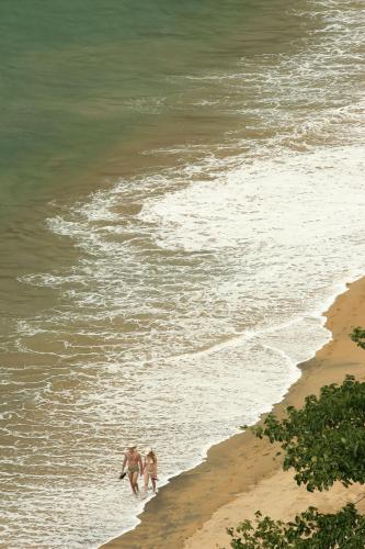 two people walking in the water on the beach at Hotel Ilhasol in Ilhabela
