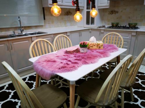 a kitchen with a white table with a pink rug at Kaleidoscope in Ajman 