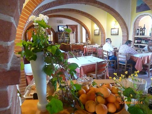 a table with a vase of oranges in a restaurant at Albergo La Foresteria in Bettolle