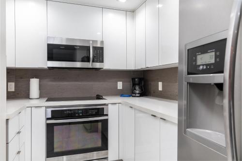 a kitchen with white cabinets and a microwave at Fortune House Hotel Suites in Miami