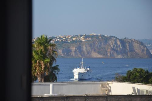 a large white boat in the water with a mountain at DC House in Procida
