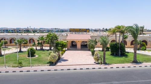 a building with palm trees in front of a street at Golden Lake Marina Hotel in El Alamein