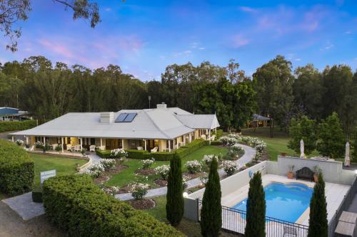 an exterior view of a house with a pool and landscaping at Thistle Hill Guesthouse - walk to many wineries and restaurants in Pokolbin