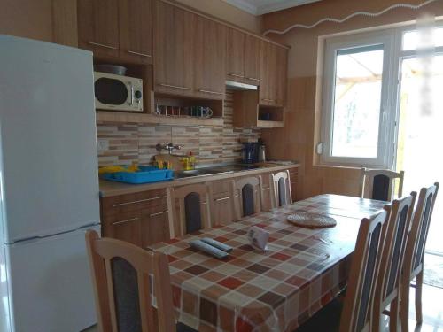 uma cozinha com uma mesa e um frigorífico branco em Family Holiday Home em Hajdúszoboszló