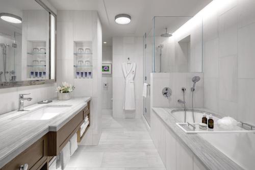 a white bathroom with two sinks and a tub at Halepuna Waikiki by Halekulani in Honolulu