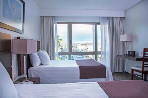 Cette chambre comprend 2 lits et une fenêtre. dans l'établissement Hotel Fray Junipero Serra, à Tepic