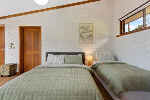 una camera da letto con due letti e un muro di mattoni di The Flaxman Studio - Panoramic Ocean Views a Port Lincoln