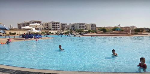 a group of people swimming in a swimming pool at شاليه بحديقة يري البحر , بانوراما بيتش ريزورت , الساحل الشمالي The North Coast , Sea View Garden Chalet in El Alamein