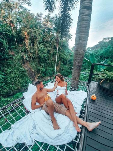 a man and a woman sitting on a bed on a balcony at Villa Cella Bella Ubud in Ubud