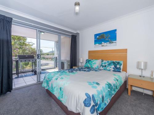 a bedroom with a large bed and a balcony at Shoal Bay Beach Apartments 18 fantastic air conditioned unit with a pool and lift in Nelson Bay