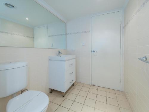 a white bathroom with a toilet and a sink at Shoal Bay Beach Apartments 18 fantastic air conditioned unit with a pool and lift in Nelson Bay