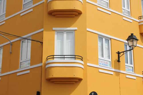 a yellow building with a balcony and a street light at Suites & Apartments DP VFXira in Vila Franca de Xira