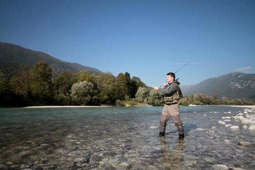 a man standing in a river holding a fishing rod at Villa Tollazzi in Logatec