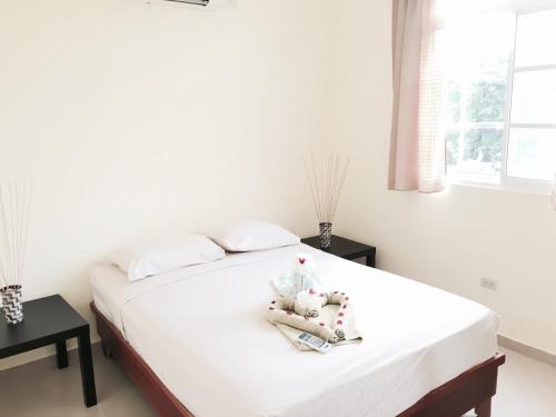 a bedroom with a bed with white sheets and a window at Costambar Beach Seaside Apartment in San Felipe de Puerto Plata