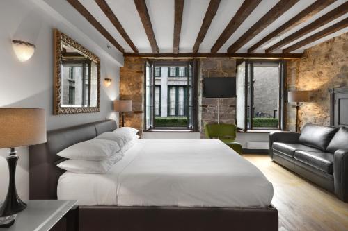 a bedroom with a white bed and a couch at Hotel Épik Montréal in Montréal